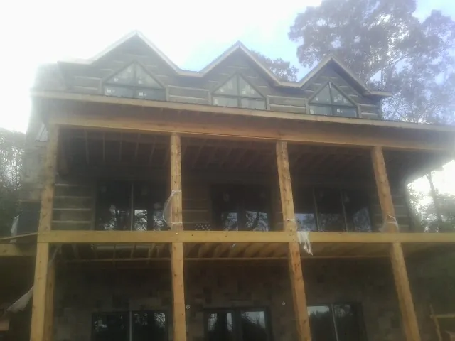 Dormers and porch framing on a large log home under construction — Roof Coating work by our crew in Saint Pauls