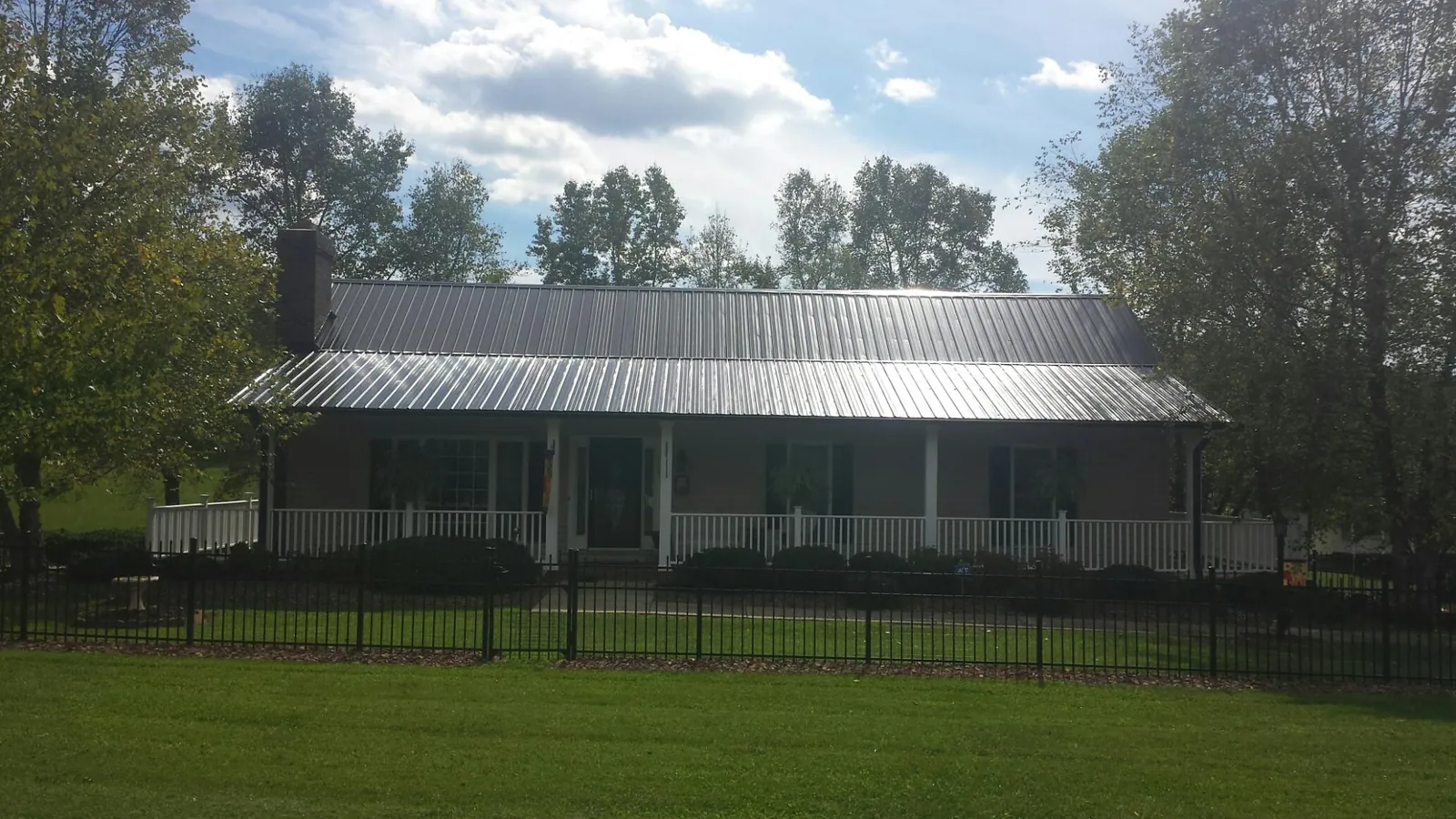 Gray metal roof on a brick ranch with a full width front porch — Gutter Guard Installation work by our crew in Saint Pauls
