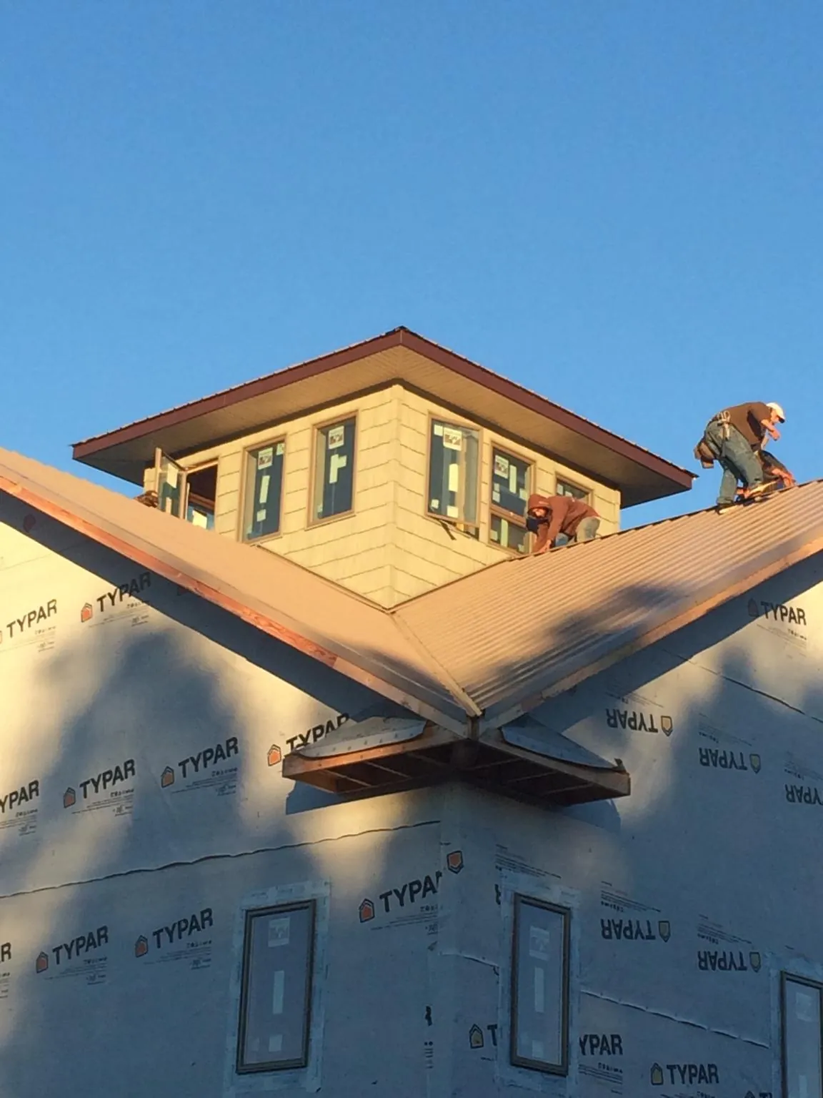 Roofers working around a rooftop cupola on a new metal roof at sunset — Roof Waterproofing in Saint Pauls by Roofing Brothers